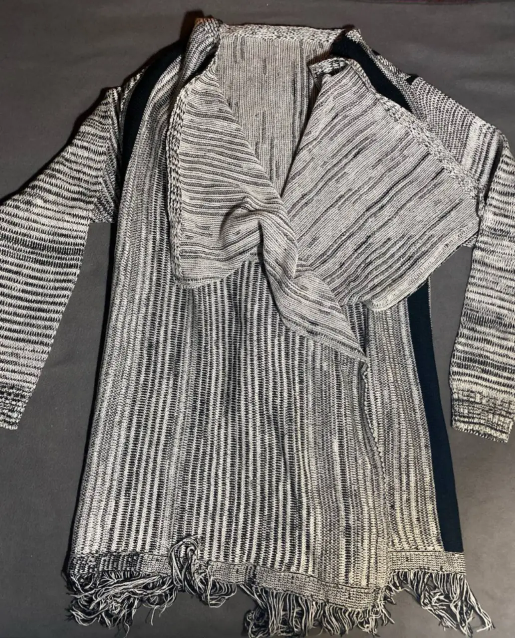 Cardigan largo de tejido rayado en tonos grises y negro, con flecos en el borde inferior. Largo 79cm y manga 54cm