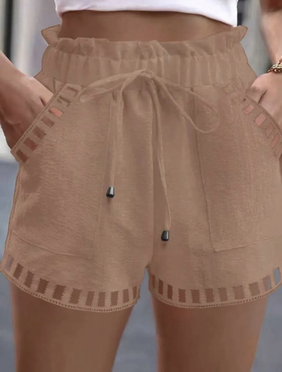 Shorts de mujer tiro alto en color marrón claro. Diseño con cintura elastizada y cordón para ajustar, bolsillos laterales y detalles calados en los bordes. Ideal para un look casual y fresco.