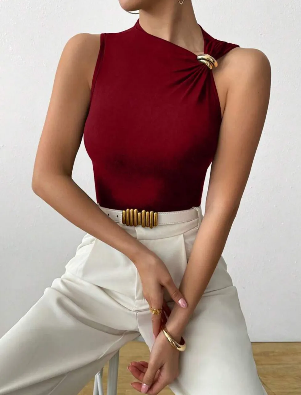 Top elegante de mujer en color borgoña, con diseño asimétrico y detalle de hebilla dorada en el hombro. Ideal para un look sofisticado y moderno.