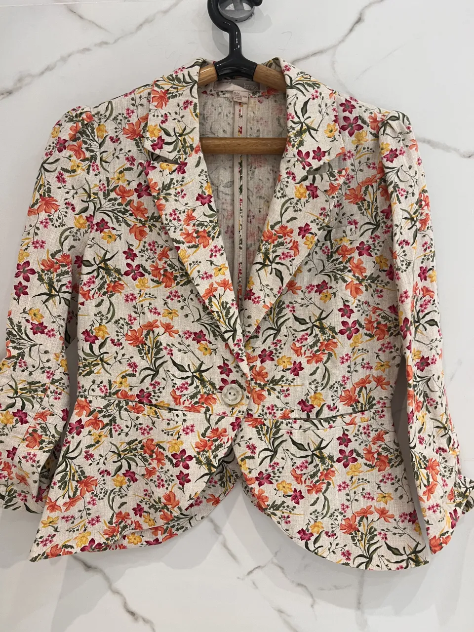 Blazer beige con estampa floral multicolor. simil lino Posee un solo botón al frente y mangas con detalle fruncido.