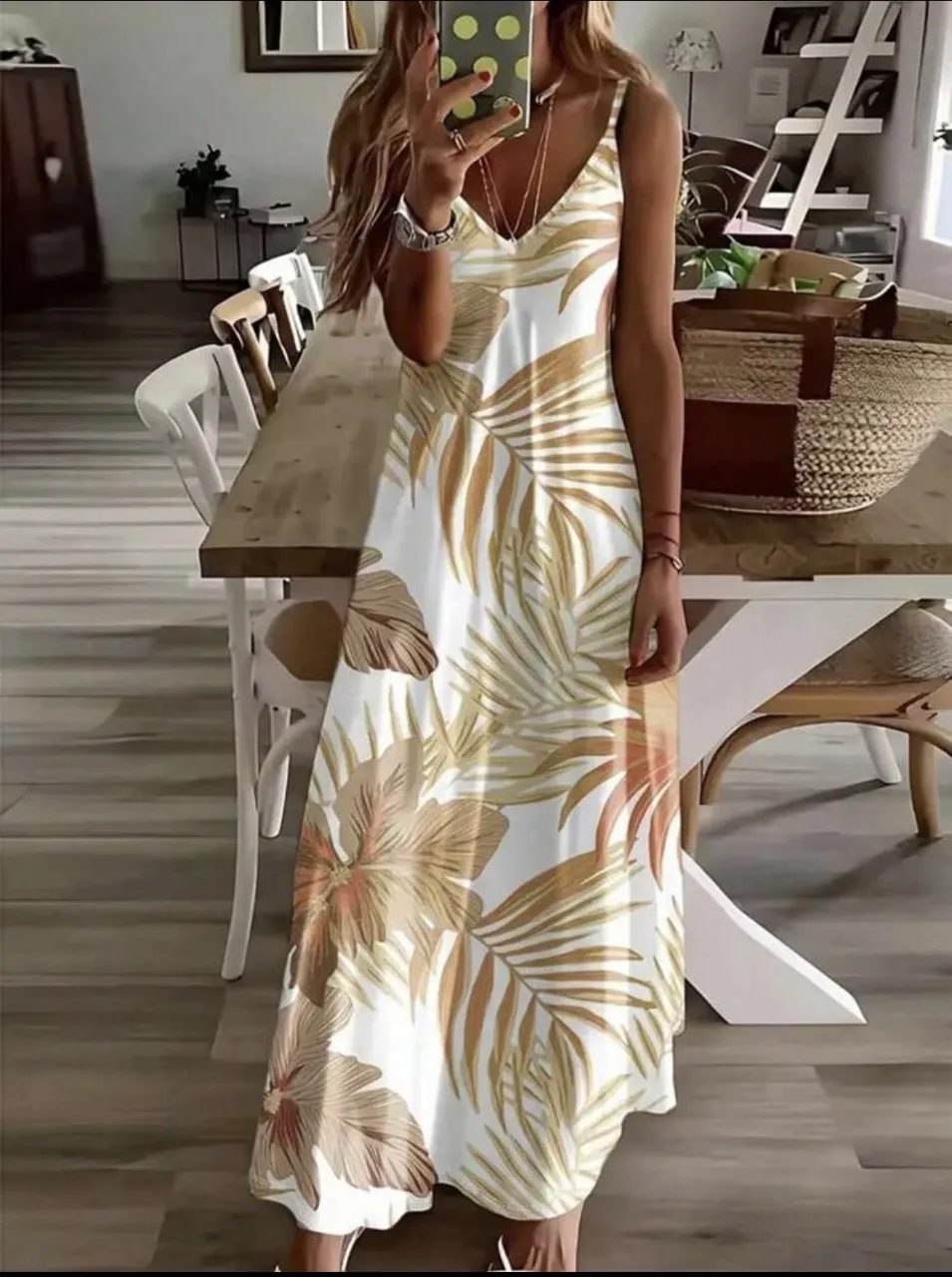 Vestido largo de mujer con estampado floral y hojas en tonos dorados sobre fondo blanco. Diseño con tirantes finos y escote en V, ideal para el verano.