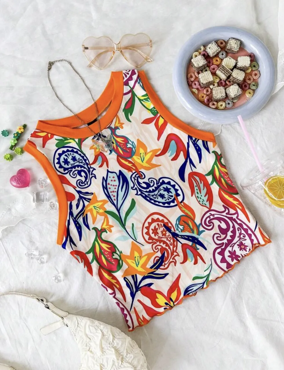Top sin mangas con estampado floral y detalles en naranja. Ideal para un look fresco y moderno.