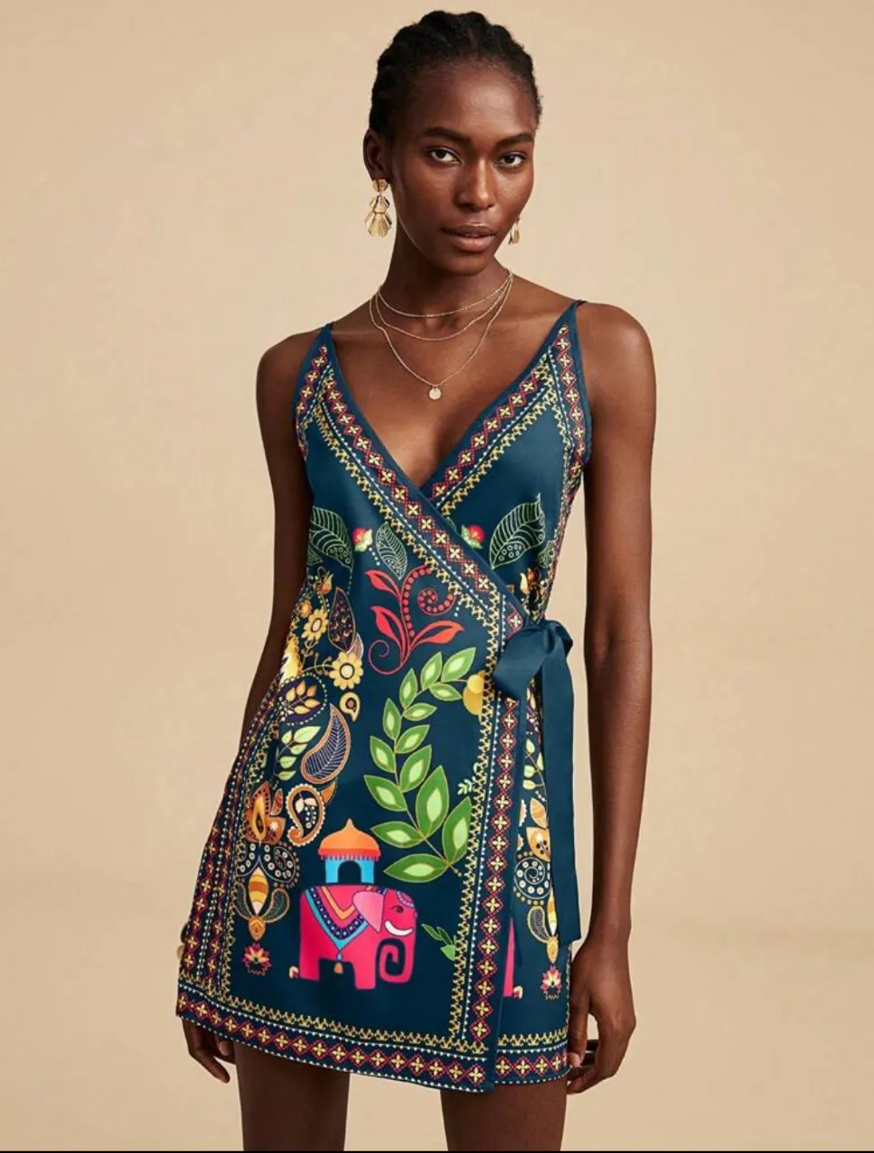 Vestido mini de mujer con estampado floral y detalles de elefantes. Diseño envolvente con lazo en la cintura y tirantes finos. Ideal para un look bohemio y fresco.
