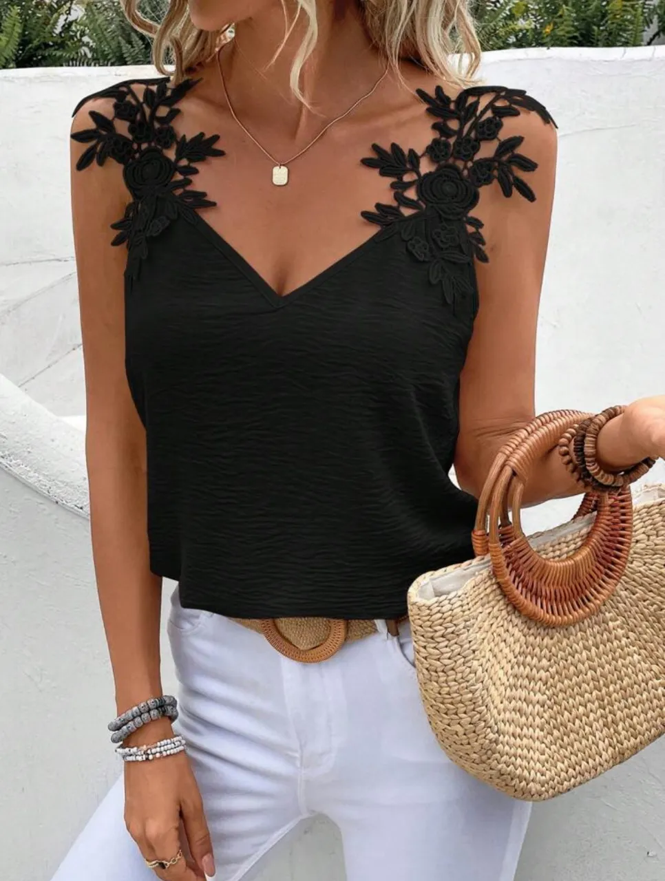Top negro con detalles de encaje floral en los hombros, escote en V y textura sutil. Ideal para un look elegante y femenino.