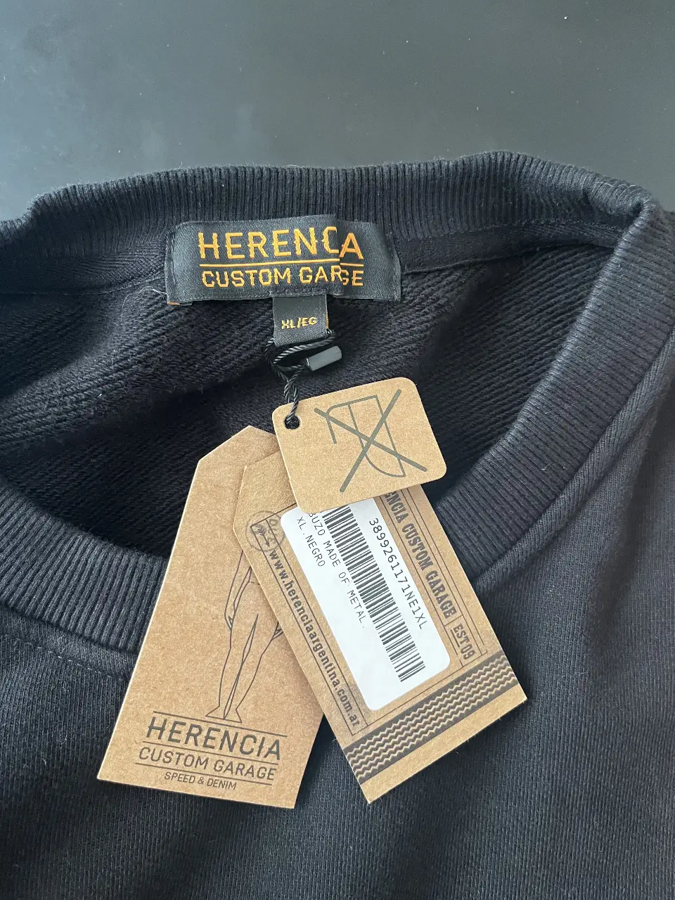 Buzo de cuello redondo negro de la marca Herencia Custom Garage. Confeccionado en algodón, este buzo presenta un diseño con estampado en la espalda y detalles en las mangas. Ideal para un look casual y urbano.