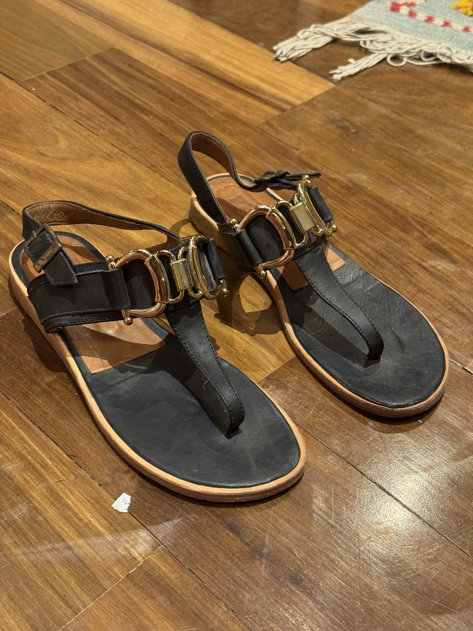 Sandalias negras de cuero con detalles dorados. Diseño elegante y cómodo, ideales para el verano. Perfectas para un look casual o para complementar un outfit más sofisticado. Tiene rota una de las plaquitas doradas, mirar quinta foto