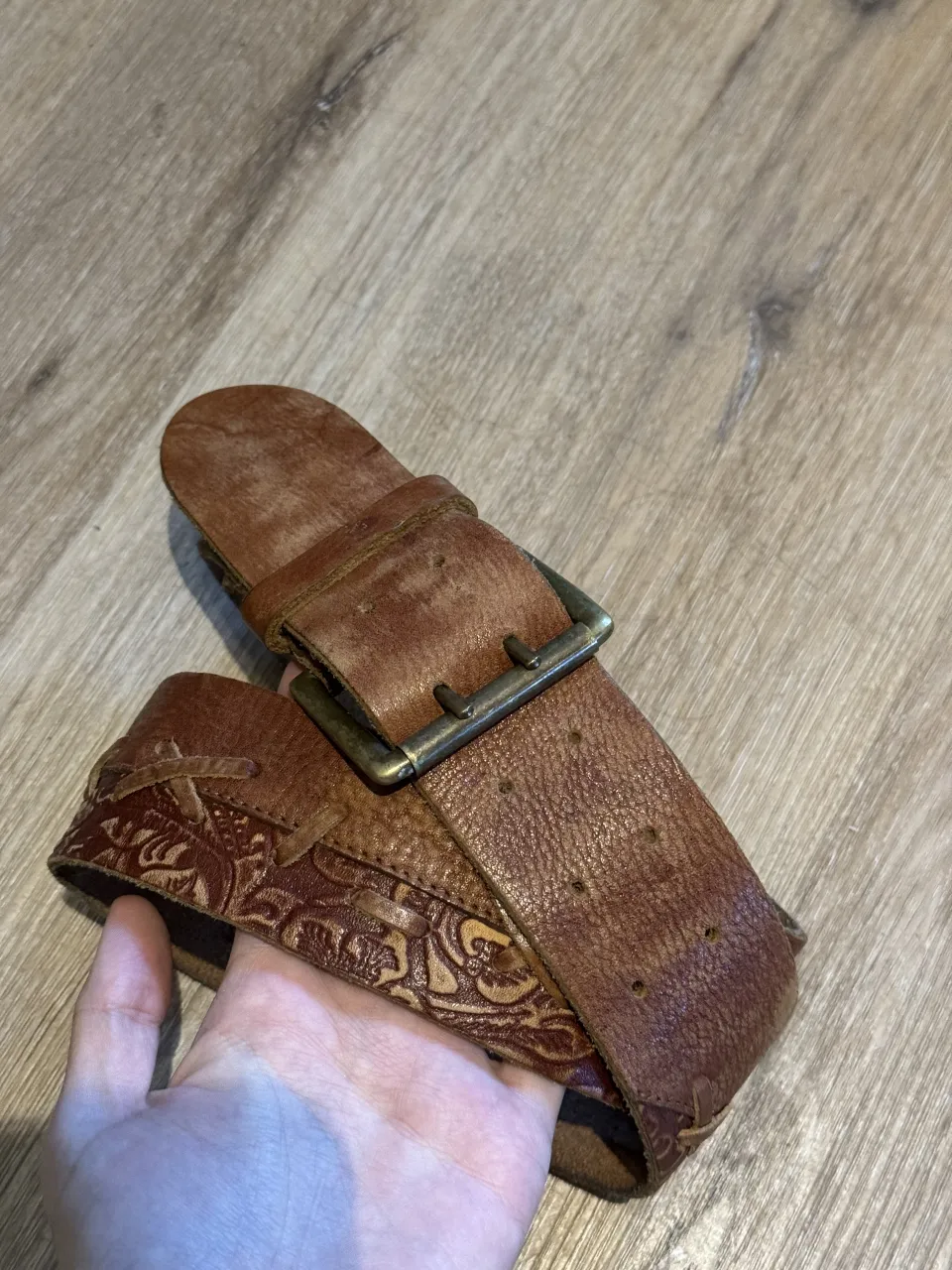 Cinturón de cuero marrón con detalles de repujado y costuras decorativas. Hebilla metálica. Es chico, tipo S/M