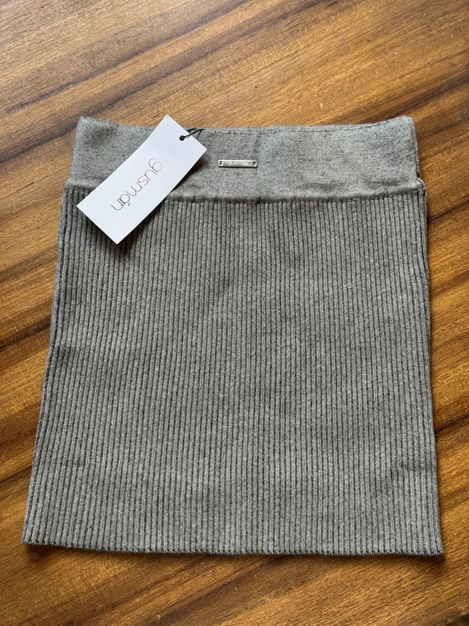 Pollera de tejido acanalado gris, con cintura elastizada y detalle de marca. Perfecta para un look casual y cómodo.