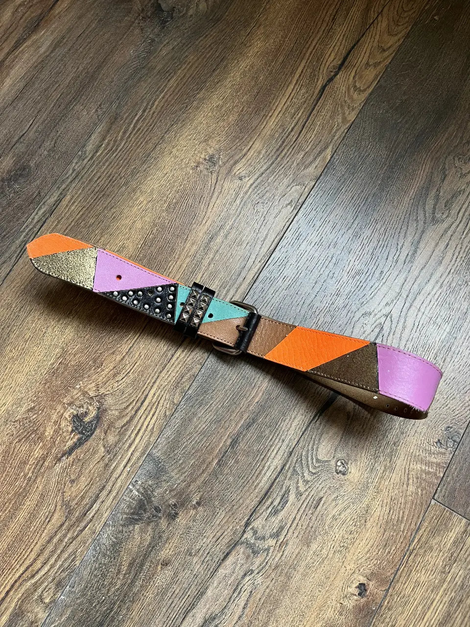 Cinturón de cuero artesanal con diseño geométrico y detalles de tachas. Estiloso y único, perfecto para darle un toque de color y personalidad a cualquier look.
