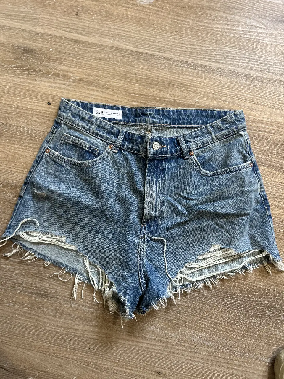 Short de jean de mujer, tiro alto, con roturas y desflecado en el borde. Ideal para un look casual y moderno.