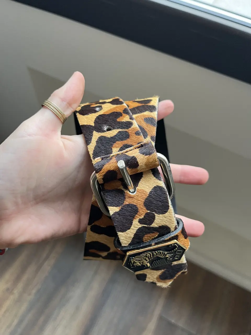 Cinturón de cuero con estampado de leopardo y hebilla plateada. Detalles de tachas negras y grabado "JAZMIN". Un accesorio audaz y con estilo para completar cualquier look.