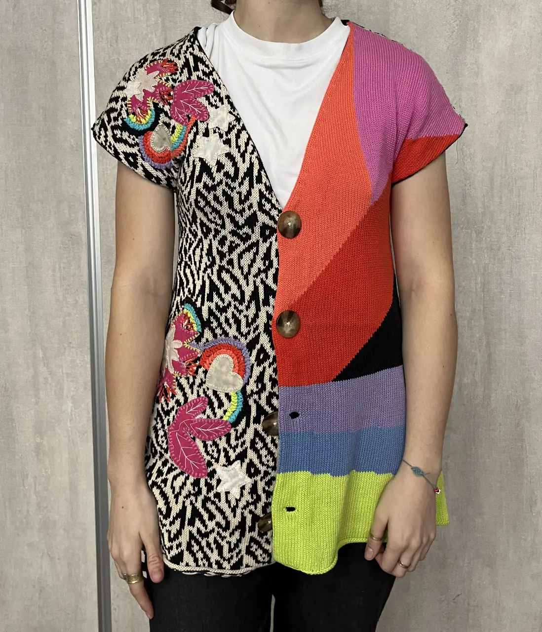 Sweater chaleco tejido con diseño patchwork y apliques bordados. Un lado con estampado de cebra y apliques de flores y corazones, el otro lado con bloques de color. Marca Jazmin Chebar.