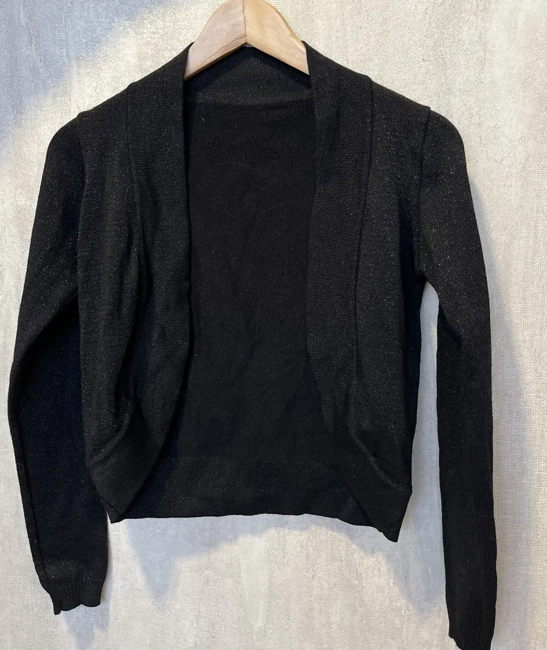 Cardigan negro de tejido fino con brillo sutil. Ideal para complementar cualquier look, perfecto para una salida o evento especial.