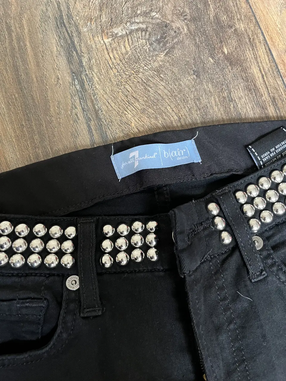 Jeans negros de tiro medio con detalles de tachas plateadas en la cintura y bolsillos traseros. Un clásico con un toque rocker para un look canchero.