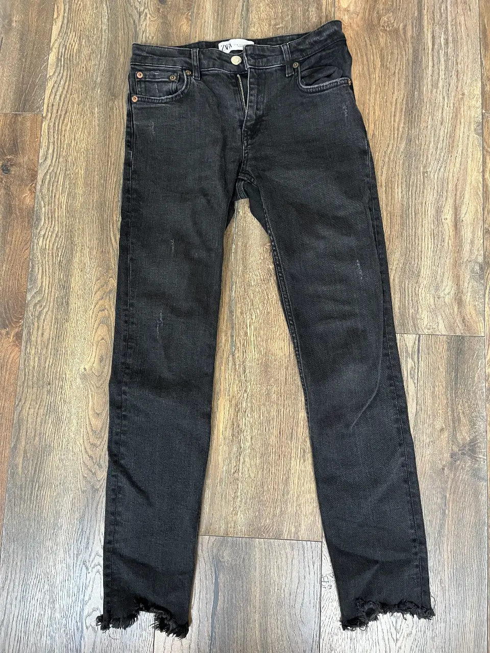 Jeans rectos negros de mujer, con detalles de desgaste y corte desflecado en el bajo. Talle 36 EUR, USA 4, MEX 26. Marca Zara.