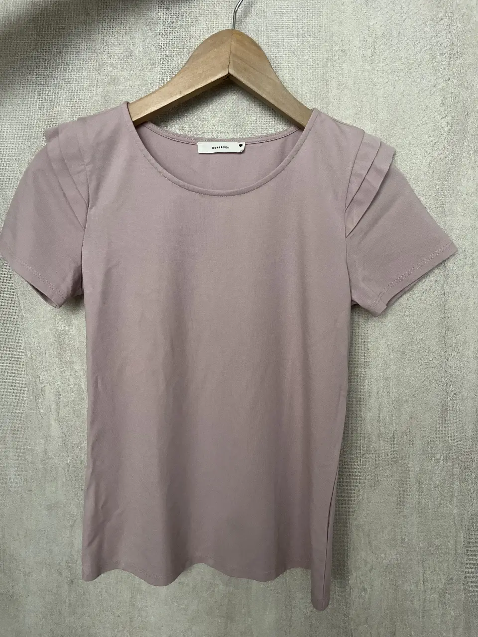 Remera de manga corta para mujer, color rosa. Con detalle de hombreras plisadas y cuello redondo. Ideal para un look casual y moderno.