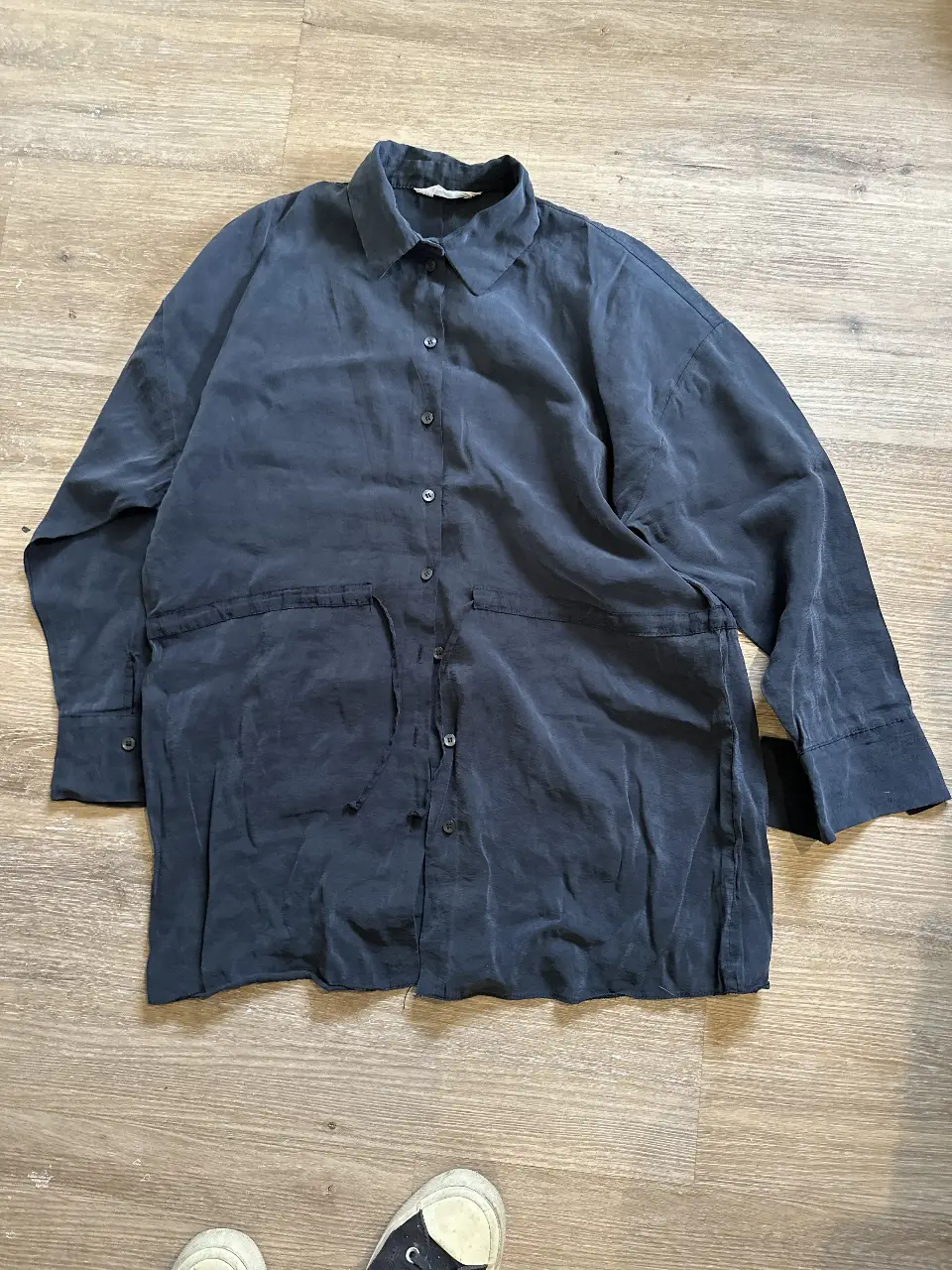 Camisa de mujer de color azul oscuro, con mangas largas y botones. Tiene un diseño holgado y bolsillos delanteros. Ideal para un look casual y cómodo.