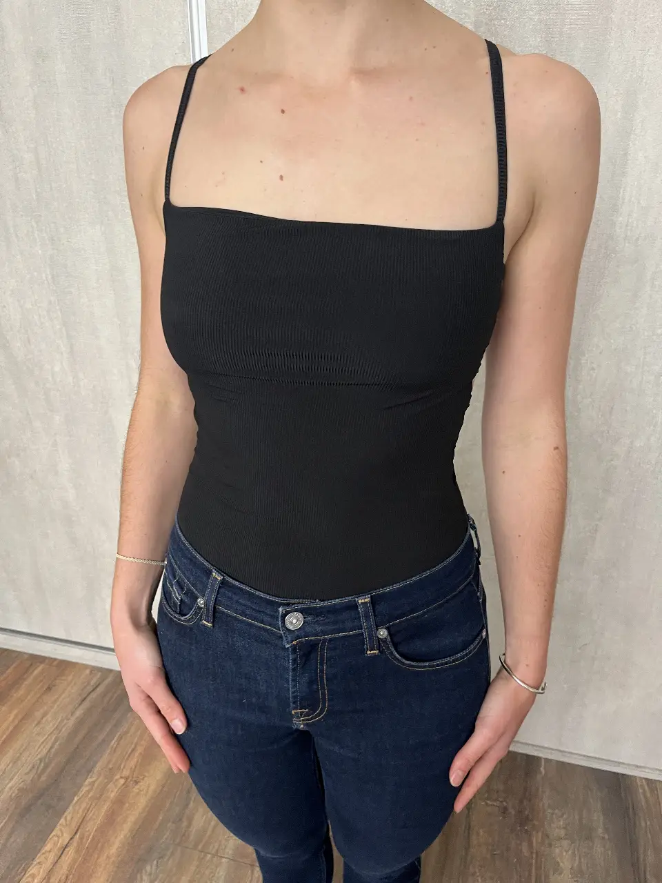 Body negro de mujer, con tiras finas y detalles cut-out en los laterales. Confeccionado en tela acanalada, ideal para un look moderno y versátil.