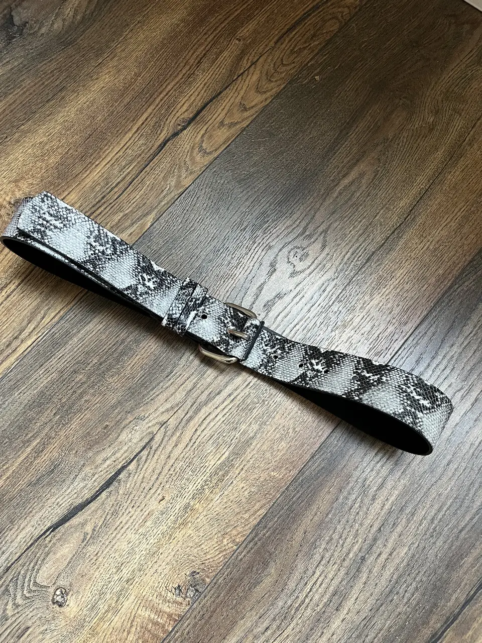 Cinturón de mujer con estampado de serpiente en tonos grises y blancos. Hebilla plateada. Marca Jazmii.
