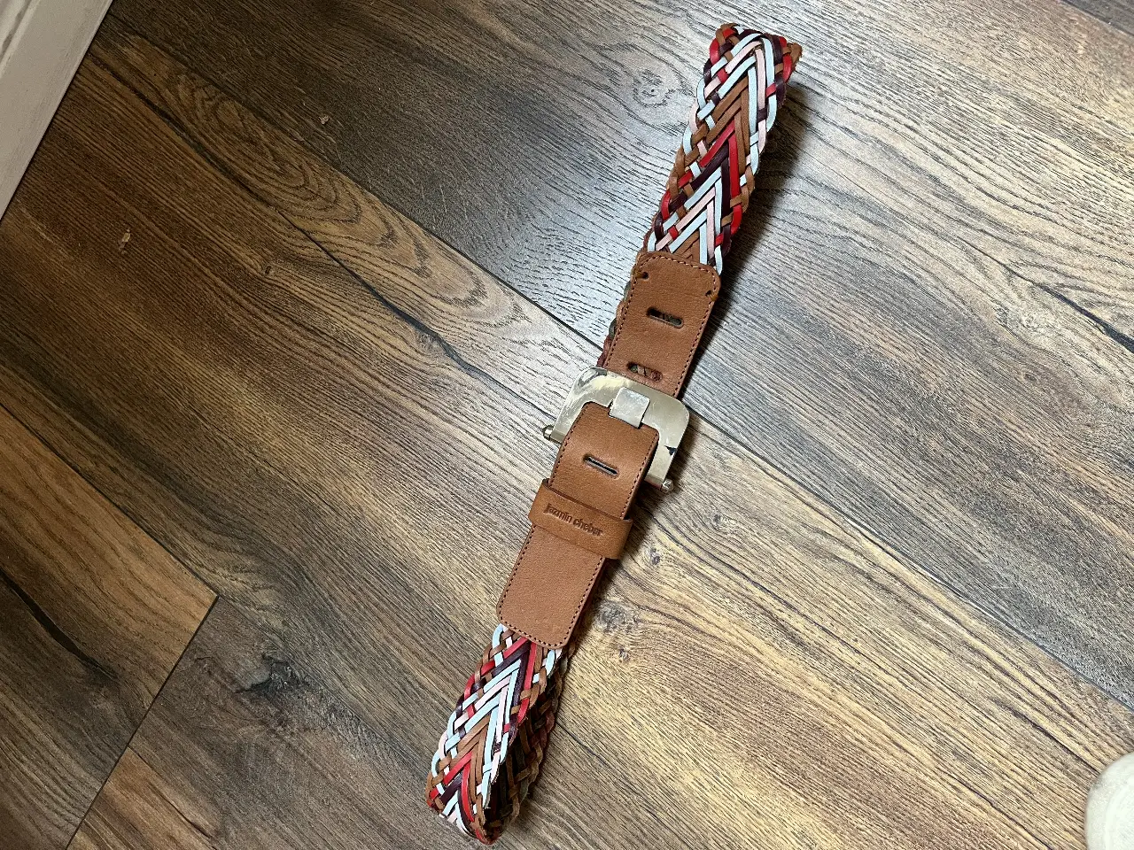 Cinturón Jazmin Chebar tejido en cuero con detalles en rojo, blanco y marrón. Hebilla plateada.