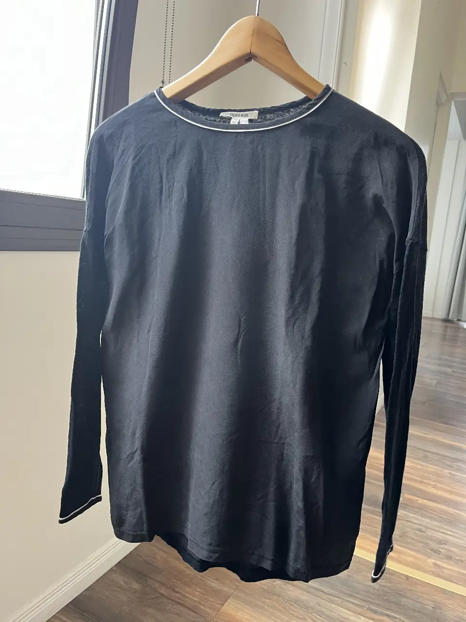 Remera manga larga negra de Etiqueta Negra, con detalles en blanco en el cuello y puños. Confeccionada en seda y lino, ideal para un look casual y elegante.