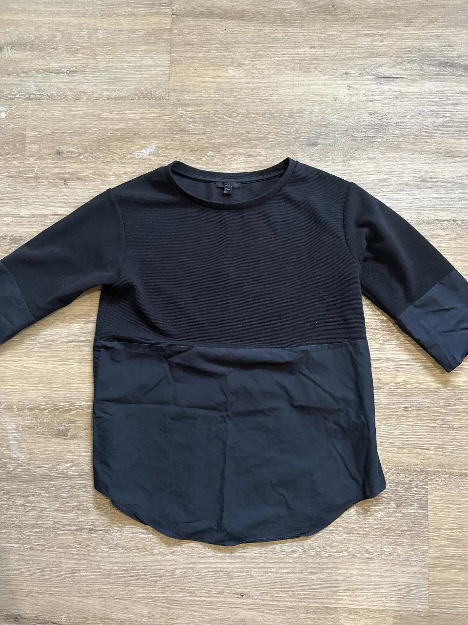 Sweater negro de COS, con mangas 3/4 y detalle de tela en la parte inferior. Ideal para un look casual y moderno.