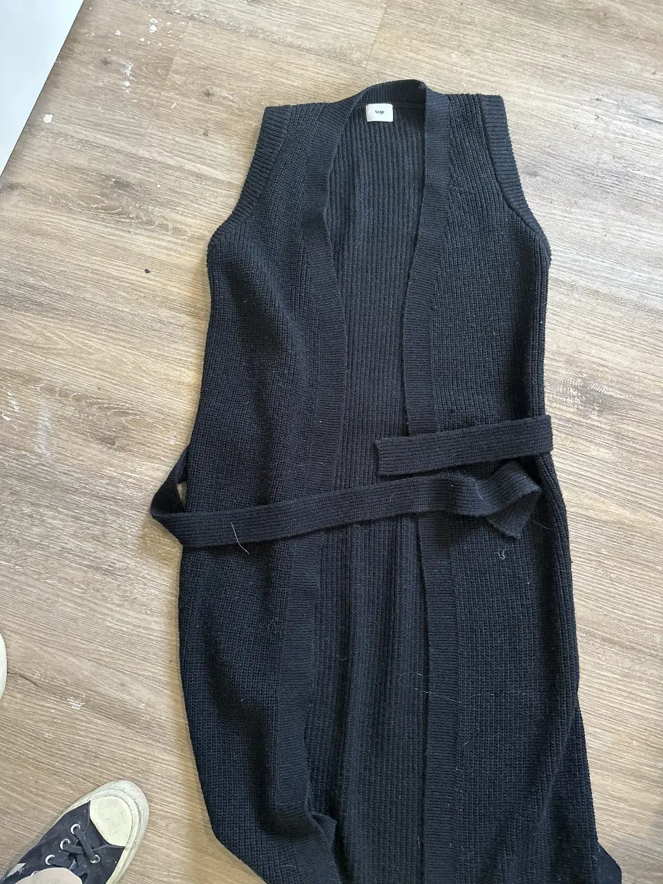 Chaleco largo de tejido de punto negro, con cinturón para ajustar en la cintura. Ideal para un look casual y moderno. 