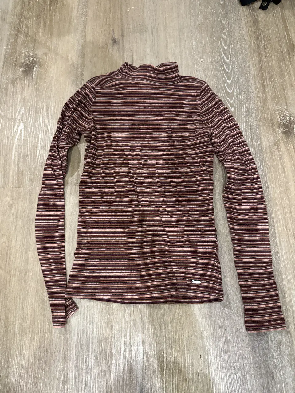 Remera manga larga de mujer Hollister a rayas horizontales en tonos marrones y rosados. Cuello alto. Talle L. Ideal para un look casual y abrigado.