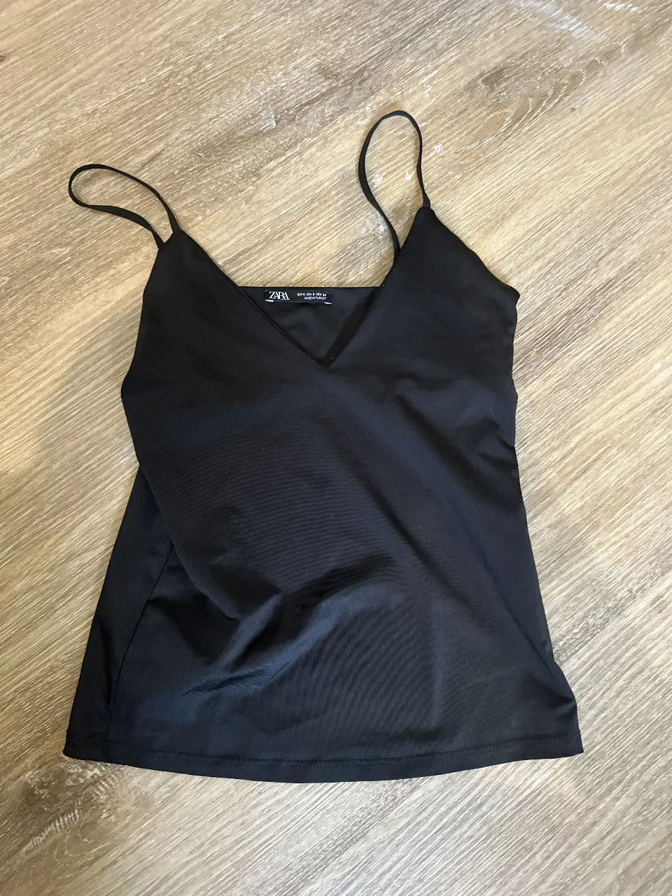 Top negro de Zara con breteles finos y escote en V. Ideal para combinar con diferentes outfits.