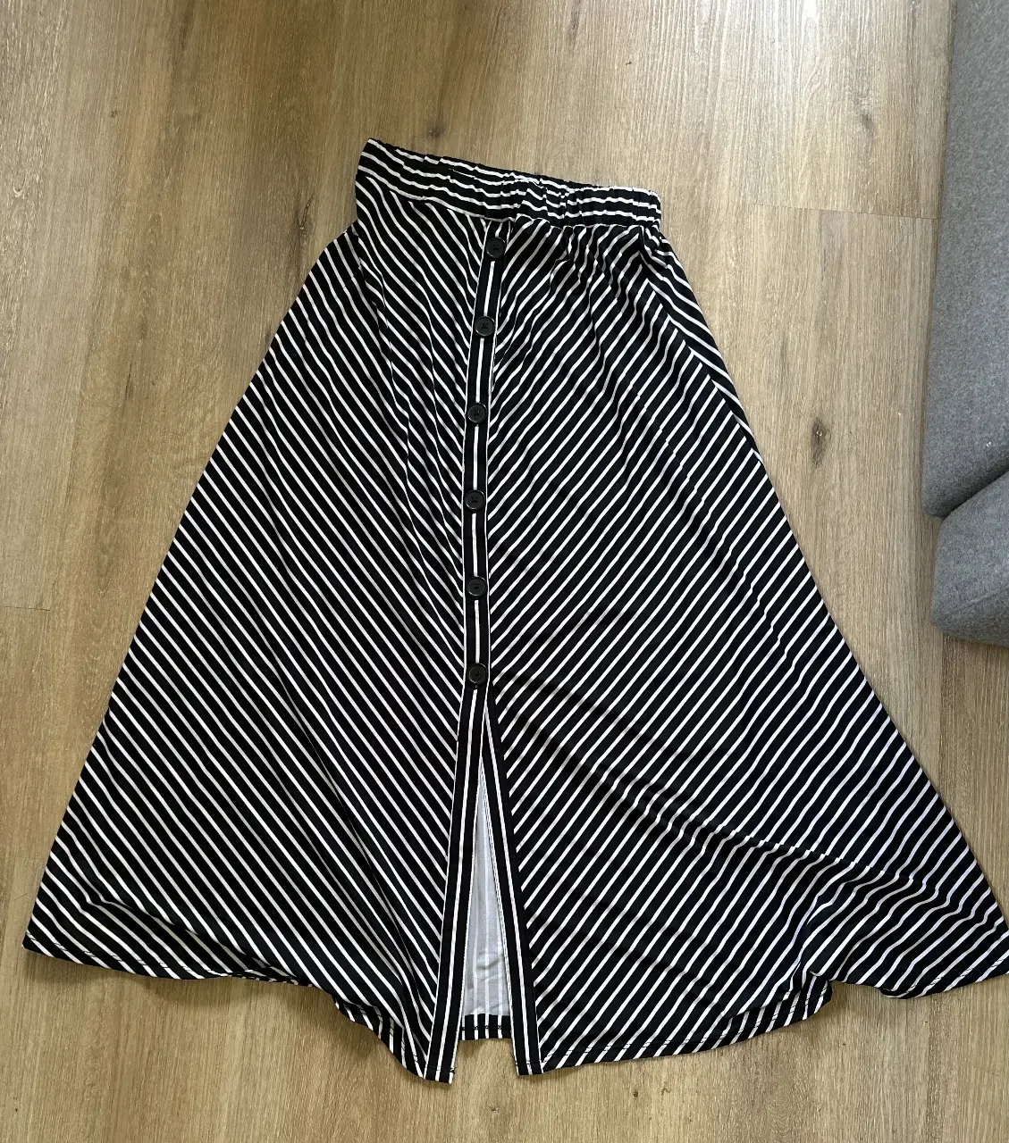 Pollera larga con estampado de rayas verticales en blanco y negro. Diseño con botones frontales y corte en A, ideal para un look casual y moderno.