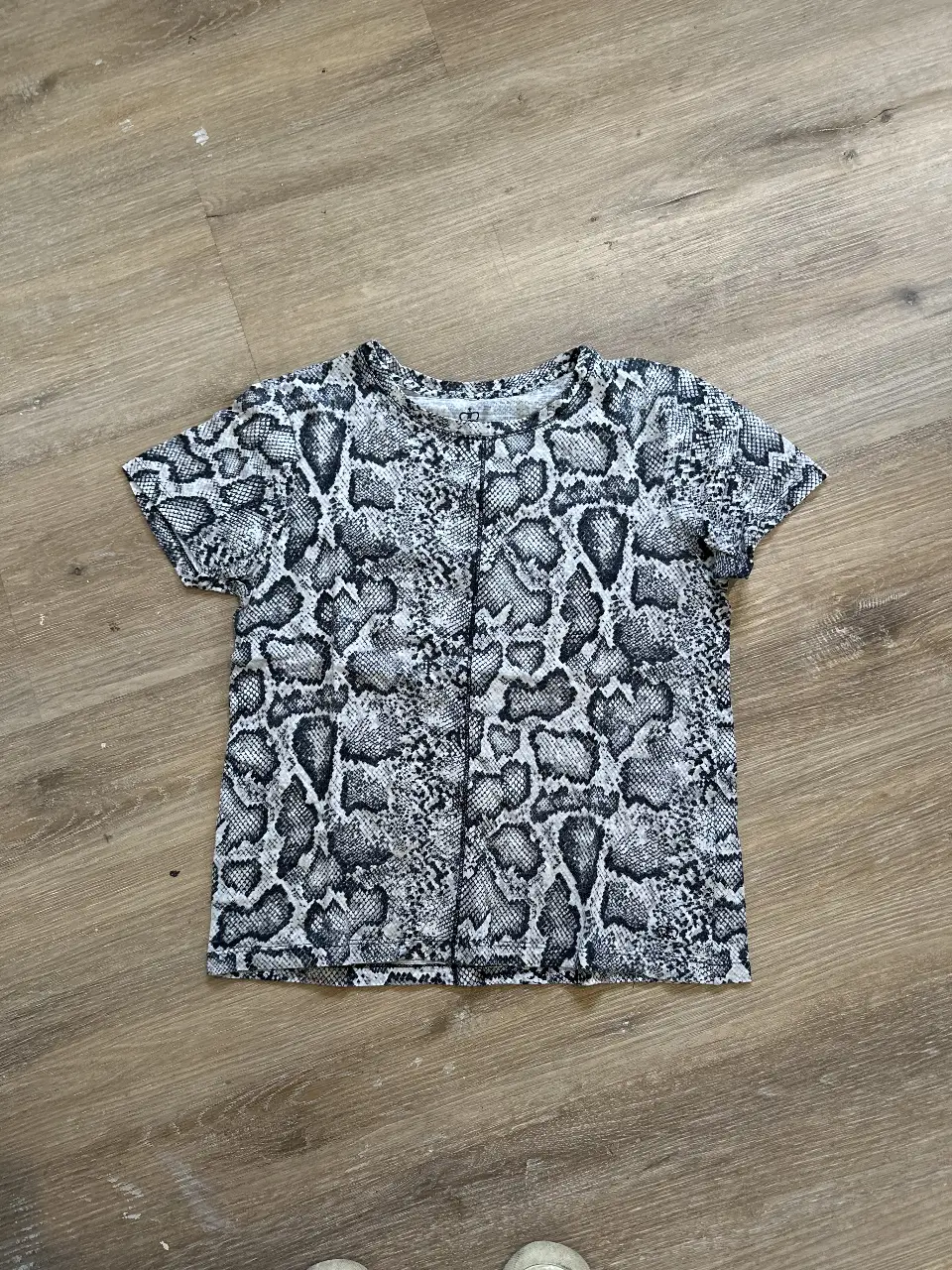 Remera de mujer con estampado de serpiente en blanco y negro. Confeccionada en 100% algodón, ideal para un look casual y moderno.
