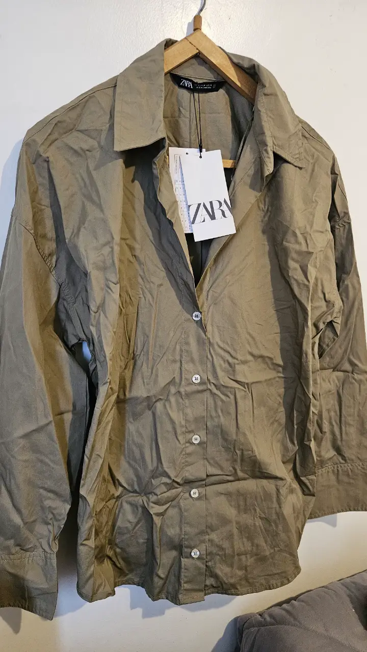Camisa de mujer de la marca Zara, color khaki (similar a verde oliva) con botones y cuello clásico en V. Ideal para un look casual y moderno.