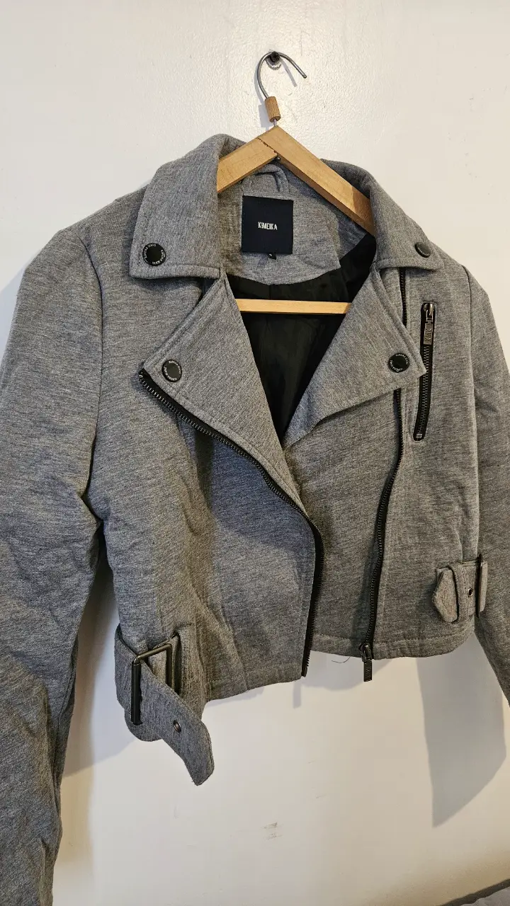 Campera biker de mujer en color gris con cierre asimétrico y detalles metálicos. Tela gruesa para invierno. Ideal para un look moderno y urbano.