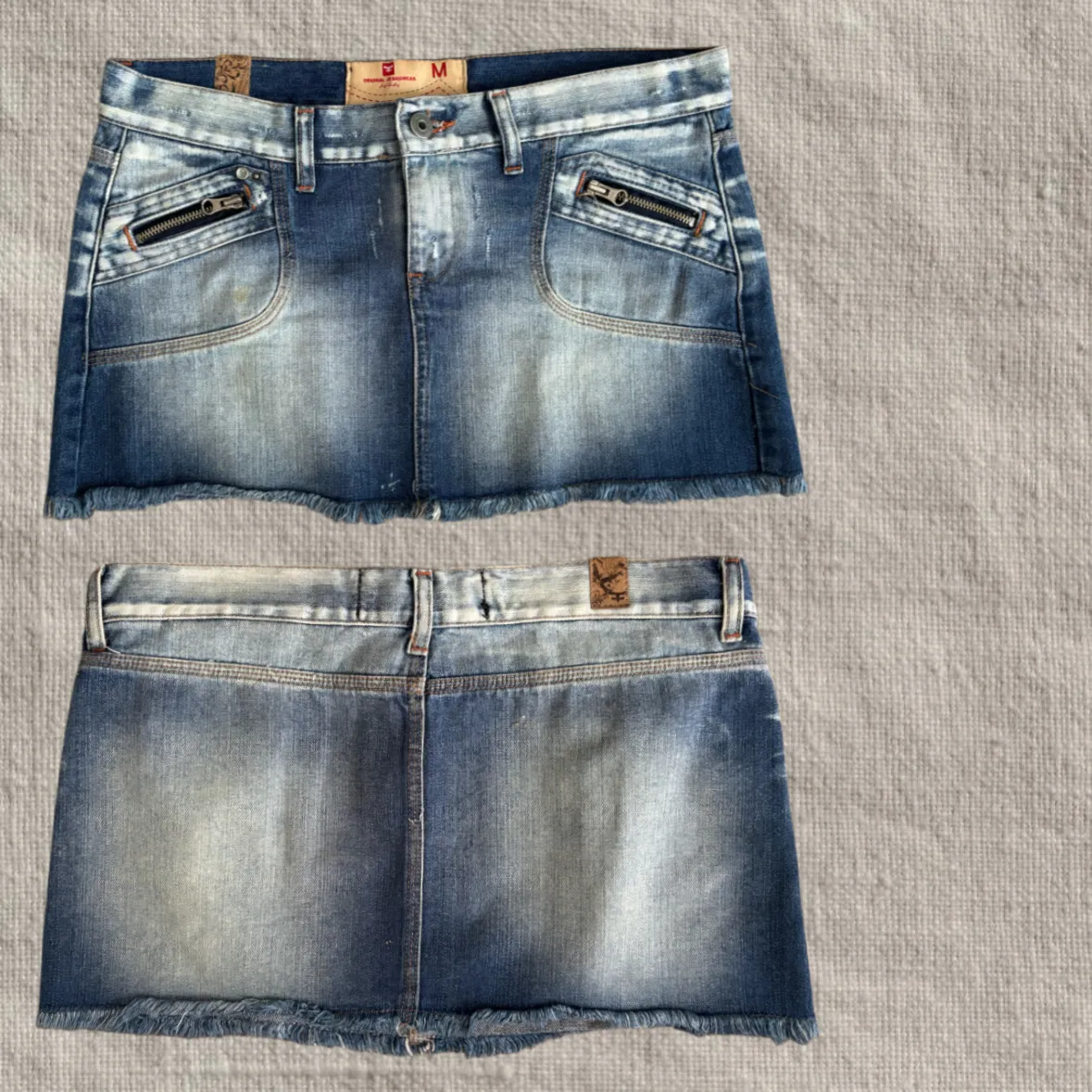 Pollera de jean corta con detalles de desgaste y roturas. Posee bolsillos delanteros con cierres metálicos y terminación desflecada en el ruedo.