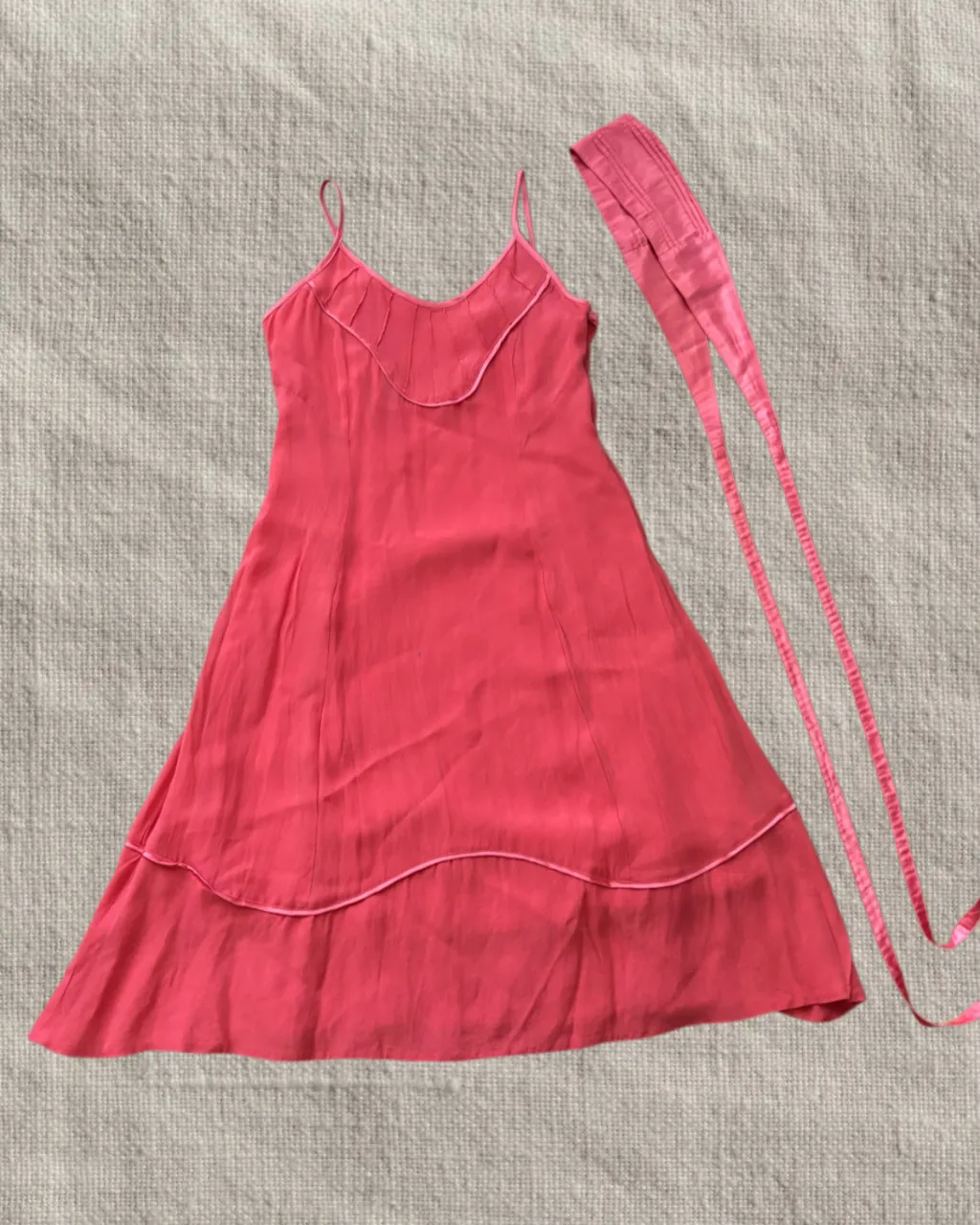 Vestido corto de breteles finos con detalle de frunces en el escote muy dosmilero. Incluye un lazo largo a tono.