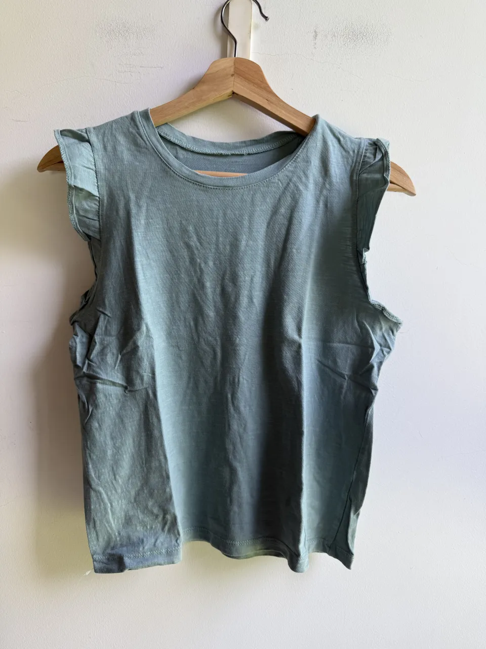 Musculosa de algodón color verde agua con detalles de volados en los hombros. Perfecta para un look casual y fresco.