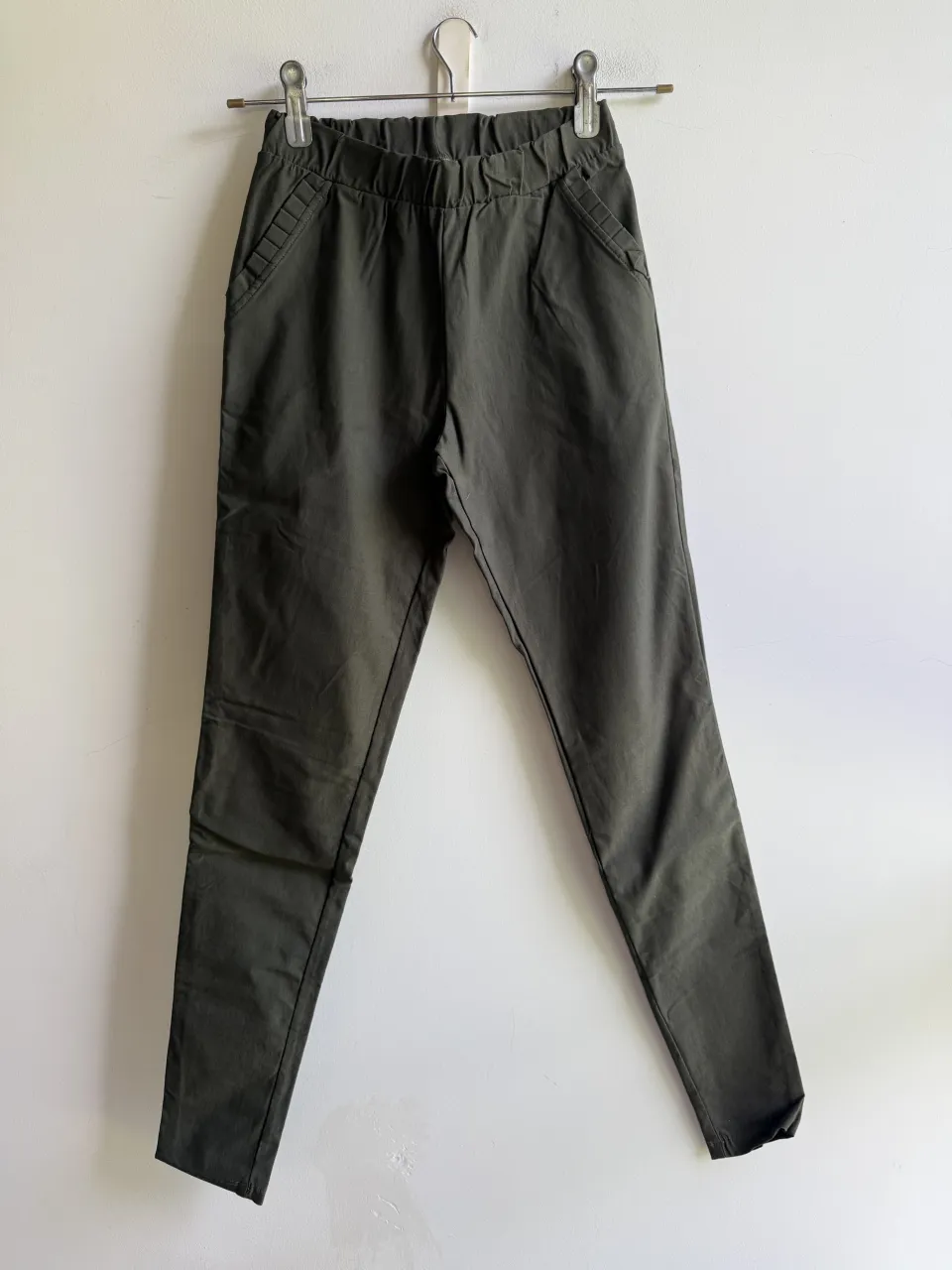 Pantalón de vestir tiro alto, color verde oscuro. Posee bolsillos delanteros y cintura elastizada. Corte recto y moderno, ideal para un look casual o de trabajo.