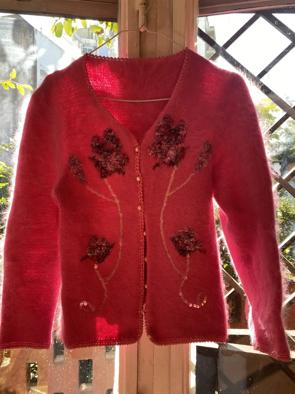 Cardigan de lana fucsia tejido con detalles florales bordados. Ideal para un look romántico y vintage.