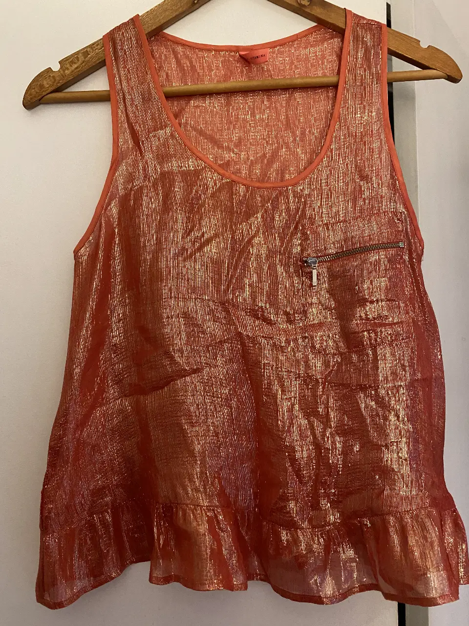 Musculosa de mujer con brillo marca Vitamina, color rojo con detalles dorados. Tiene un bolsillo con cierre y volados en la parte inferior. Ideal para una salida.
