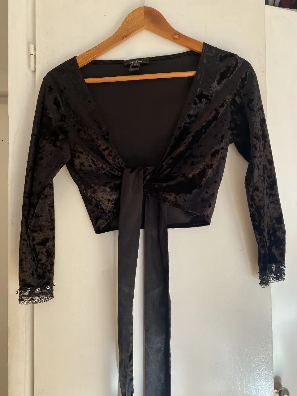Top de terciopelo negro con mangas largas y detalle de lazo en la cintura. Detalles de encaje y lentejuelas en los puños. Mango Suit, talle S.