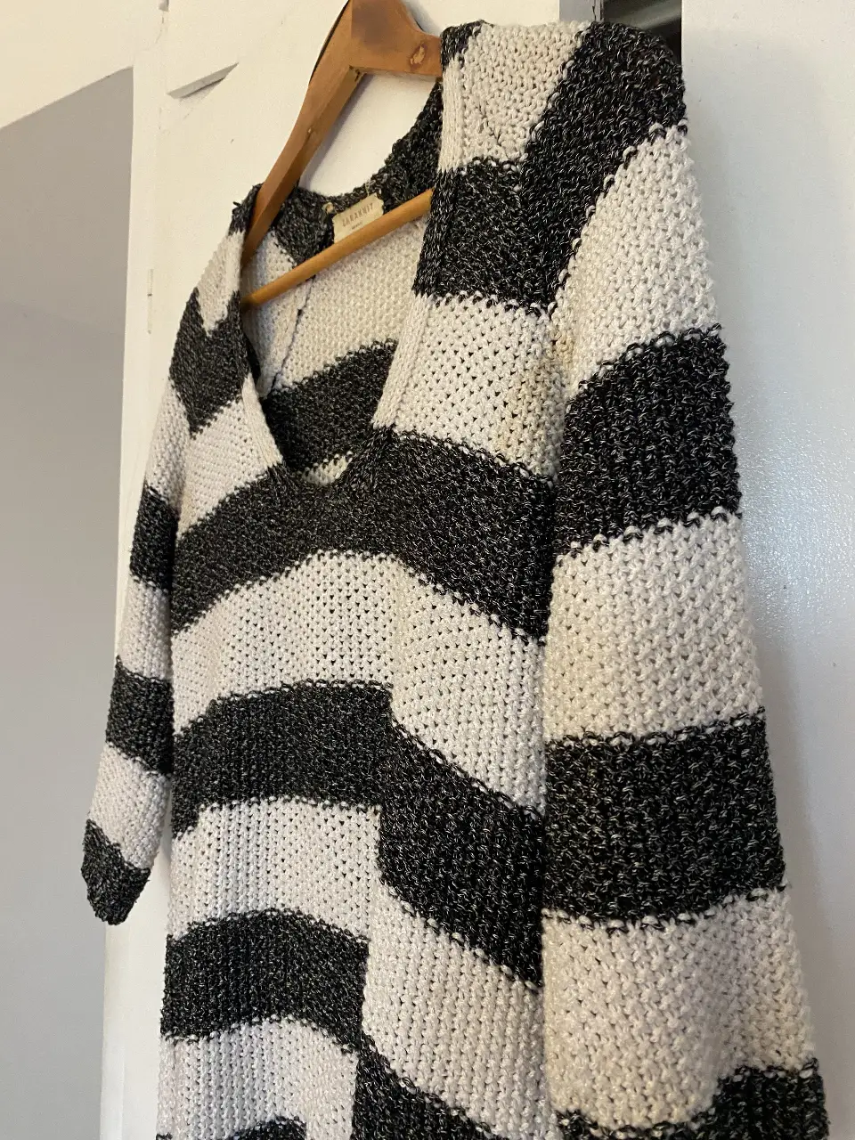 Sweater de punto a rayas horizontales en blanco y negro, con cuello en V. Ideal para un look casual y cómodo en primavera.