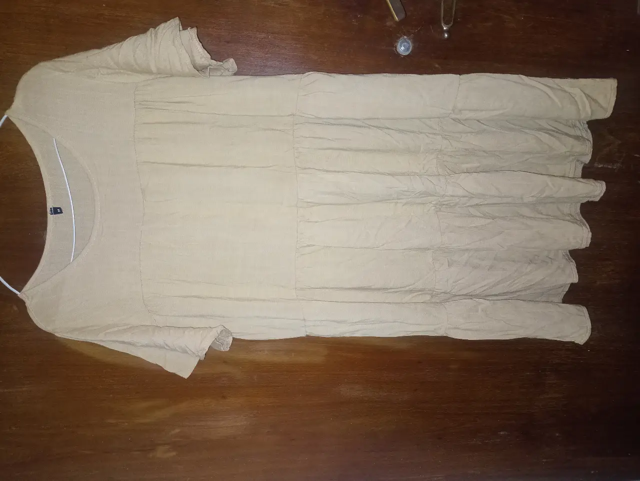 Vestido midi de color crudo, con mangas cortas y detalles plisados. Ideal para un look casual y cómodo.