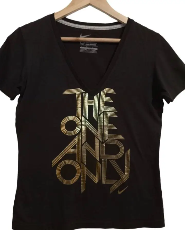 Remera negra de mujer con estampado dorado "THE ONE AND ONLY". Cuello en V. Ideal para un look casual y moderno.