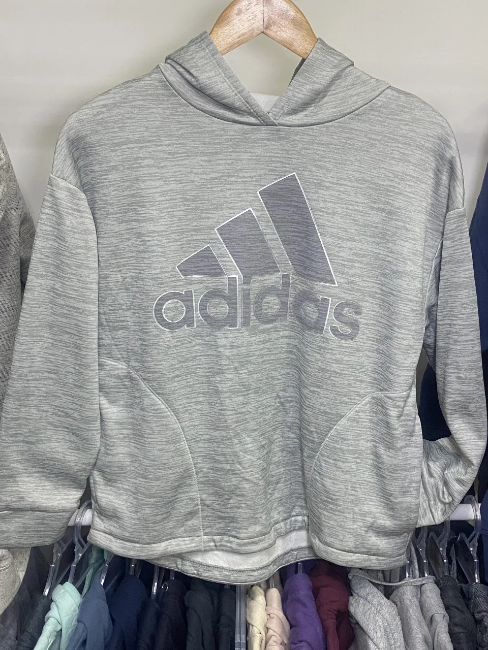 Buzo canguro Adidas gris, con capucha y el logo de la marca en el frente. Talle XL, ideal para un look casual y cómodo.