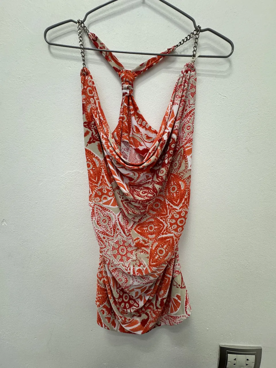 Top de mujer con estampado floral en tonos naranja y blanco. Diseño con cuello halter y detalle anudado. Ideal para un look fresco y moderno.
