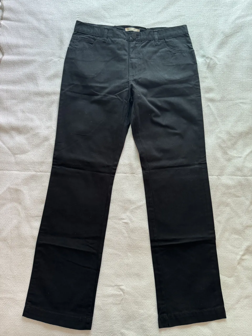 Pantalón negro de vestir con bolsillos delanteros y traseros. Cierre y botón en la parte frontal.