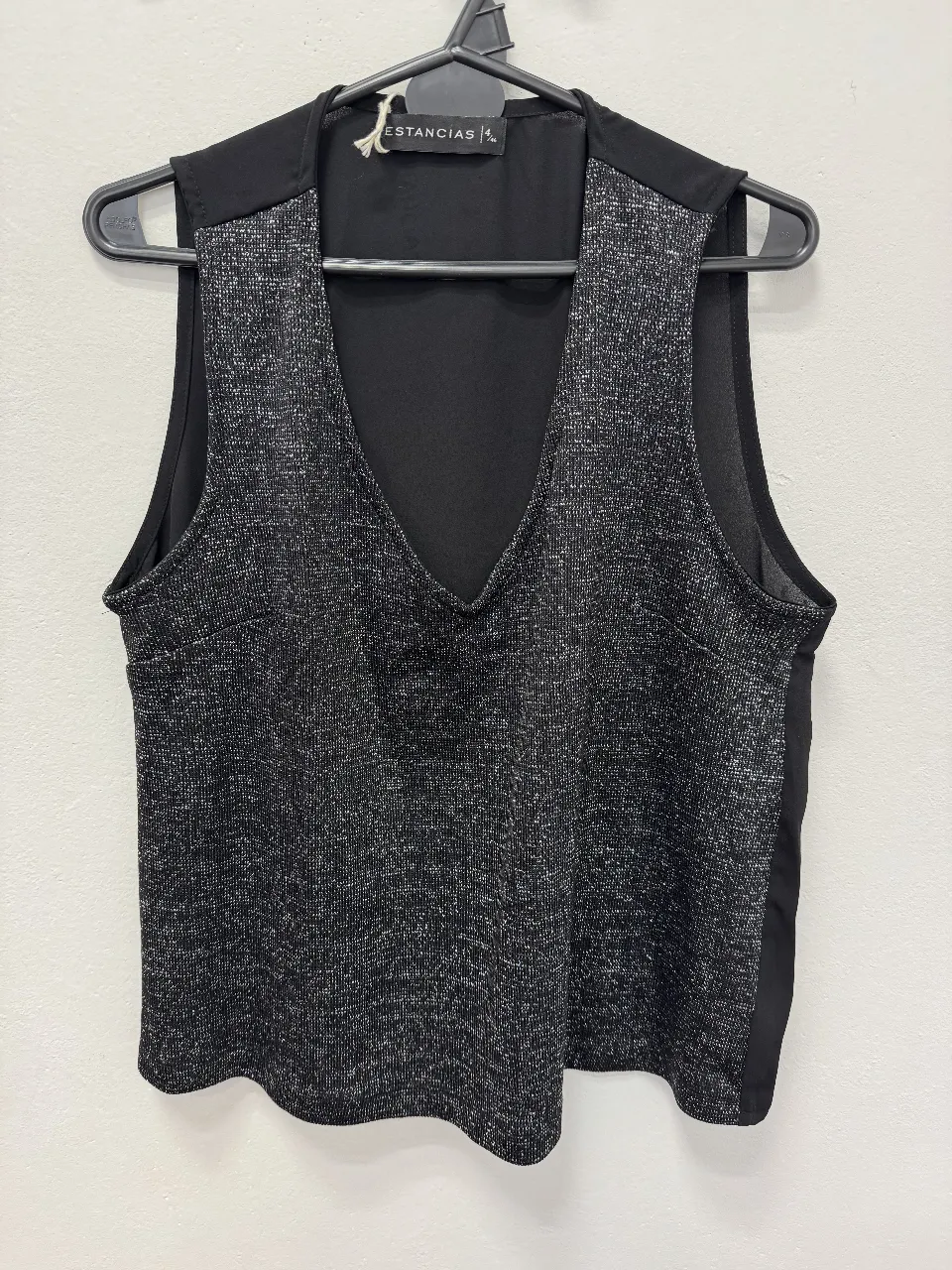 Top negro con detalles plateados, ideal para una salida. Diseño elegante y moderno.