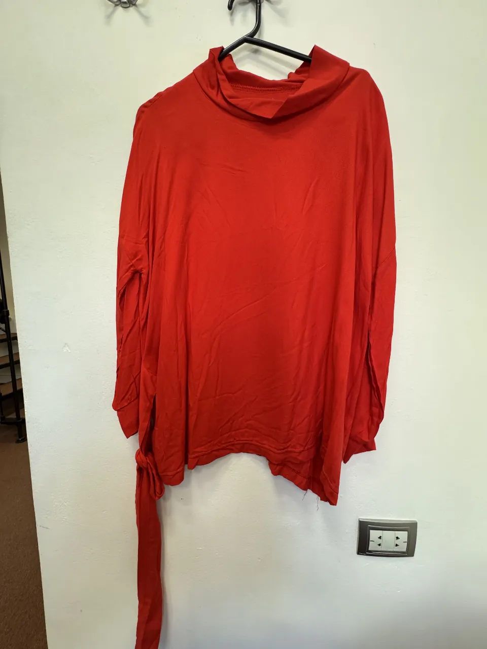 Blusa roja de manga larga con cuello alto y detalle de lazo en la cintura. Ideal para un look moderno y sofisticado.