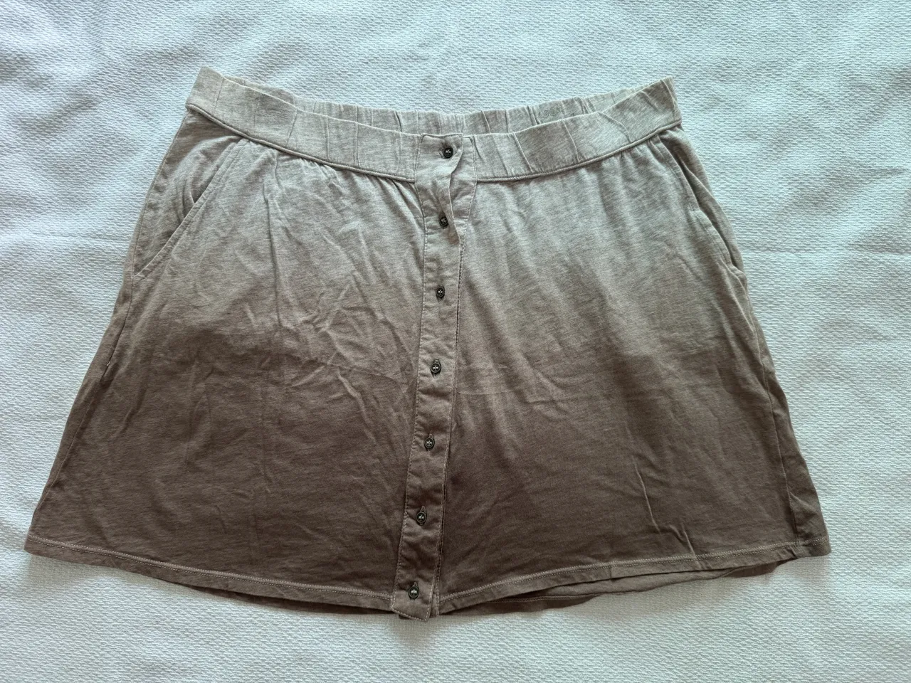 Pollera corta de algodón con cintura elastizada y botones al frente. Posee bolsillos laterales.