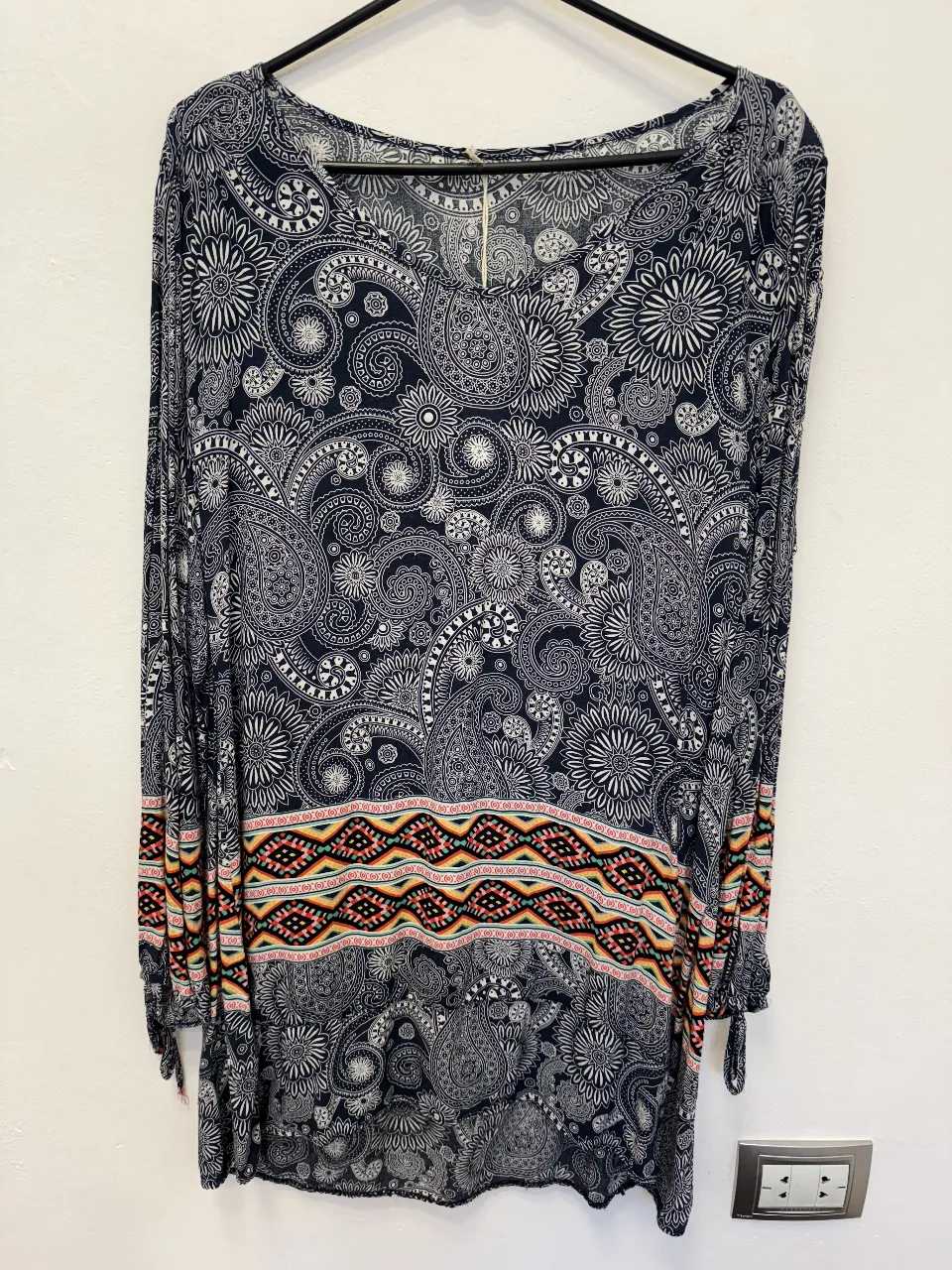 Vestido largo de mujer con estampado paisley en tonos azul y blanco. Detalles en la cintura con diseño geométrico en colores vibrantes. Mangas largas con puños ajustados. Ideal para un look bohemio y elegante.
